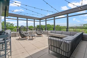 a rooftop patio with couches and chairs and glass walls